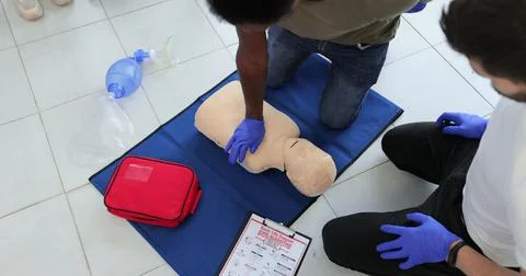 Closeup of students practicing CPR chest compression on teen dummy. Stockfoto's