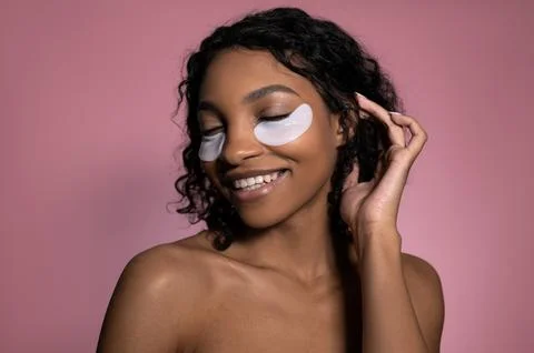 Closeup studio shot of smiling happy dark skinned girl with patches under eyes Stock Photos