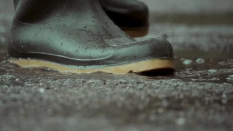 A closeup of stylish boots splashing through puddles on a rainy day Stock Footage 313283555