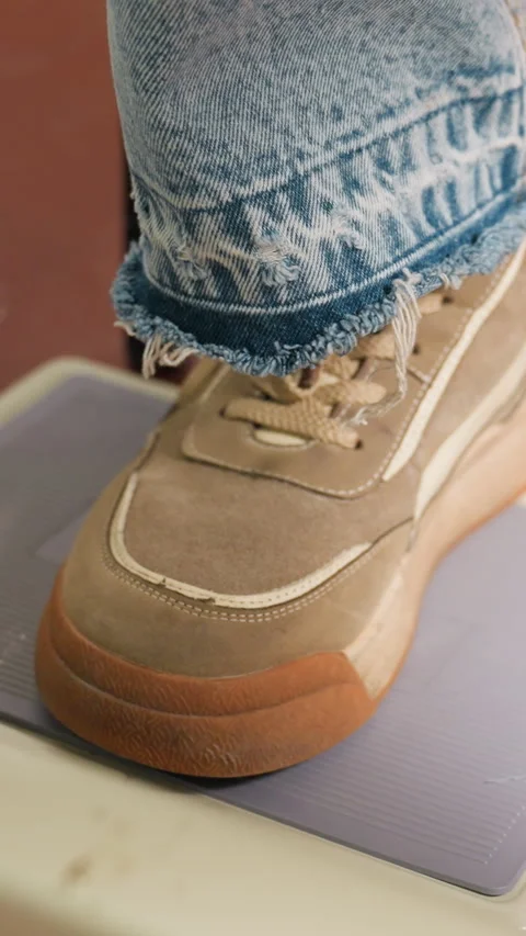 Closeup suede sneaker toe on textured mat, frayed denim cuff and laces visible Stock Footage 329513329