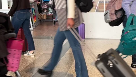 Closeup suitcases being pulled by passengers walking thru busy airport terminal Stock Footage 256247158