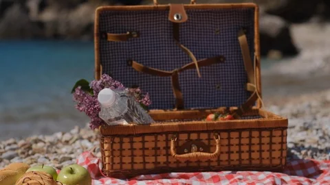 Closeup of summer picnic basket with water, fruit and croissant near sea Video stock 106938014
