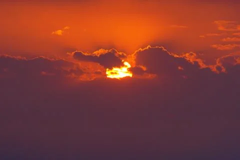 Closeup of sun behind clouds at sunset Stock Photos