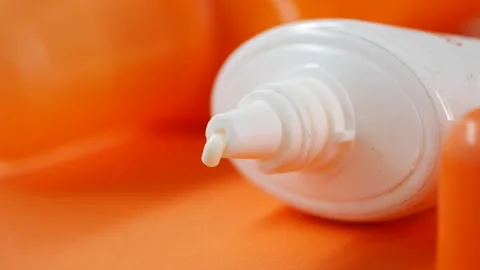 Closeup of sunscreen cream and container on a orange background Stock Footage 338217834