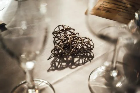 Closeup of table decoration. Art object, wicker heart shape. Shadow on white Stock Photos