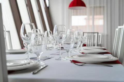 A closeup of table set with plates, glasses and chairs Stock Photos