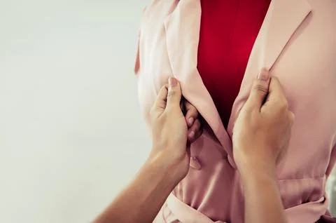 Closeup tailor hand button up pink pastel color woman fashion suit on red m.. Foto stock