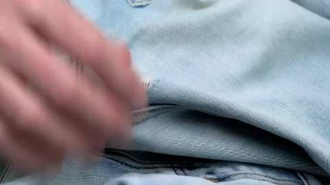 Closeup of a tailor hands checking holes on women's jeans before darning them. Stock Footage 254339040