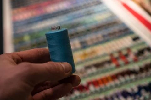 Closeup of tailors hands choosing thread color from box of different sewing Stock Photos
