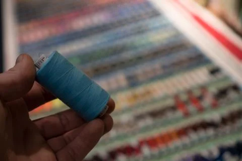 Closeup of tailors hands choosing thread color from box of different sewing Stock Photos