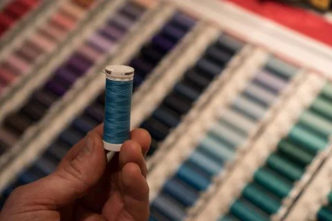 Closeup of tailors hands choosing thread color from box of different sewing Stock Photos
