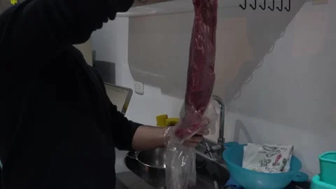 Closeup taking meat out of a bag for grilling with a man's hand in the kitchen Vidéo 155787177