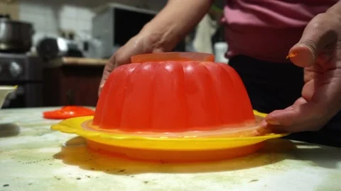 Closeup taking out orange jelly mold with hands on kitchen table in 4k Stock Footage 171996215