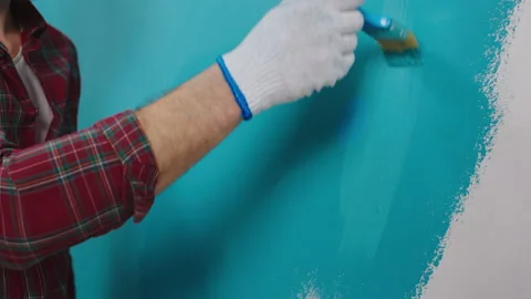 Closeup taking video of a small brush painting wall in a blue colour man wearing Video stock 171222390