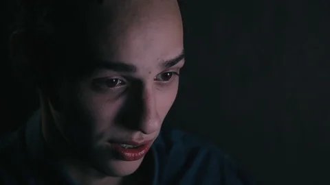 Closeup of talking man in front of computer. Monitor light on men's face at Видео 99051250