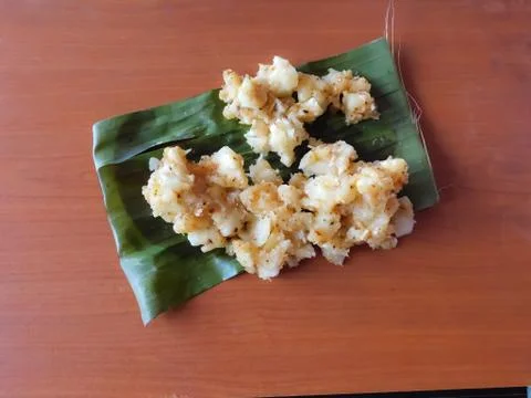 Closeup of tapioca curry in a banana leaf isolated on a wooden surface Stock Photos