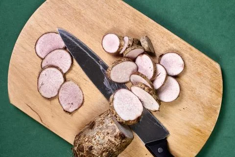 Closeup of taro root vegetable, eddo malanga, green background Stock Photos