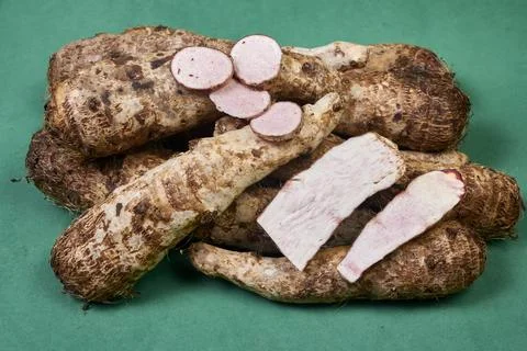 Closeup of taro root vegetable, eddo malanga, green background Stock Photos