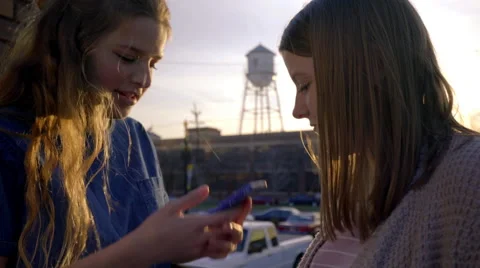 Closeup Of Teens (In City At Sunset) Talking, Girl Checks Her Phone Stock Footage