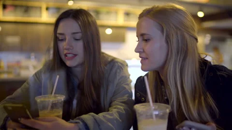 Closeup Of Teens Drinking Coffee, And Looking At A Smart Phone, In Coffee Shop Stock Footage