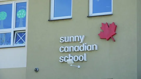Closeup on the text above a school entrance: Sunny Canadian School on a sunny Stock Footage