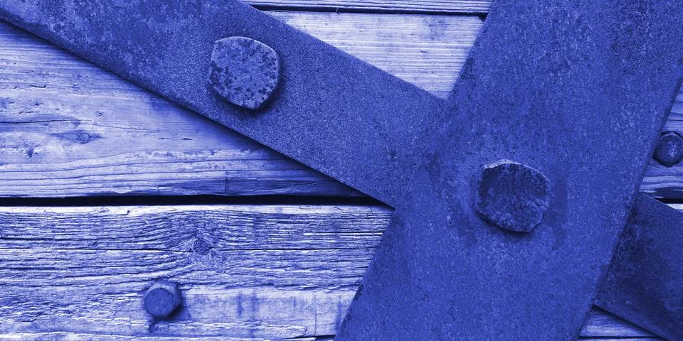 Closeup texture of rusty iron sheets bolted to aged wooden planks in blue colors Stockfoto's