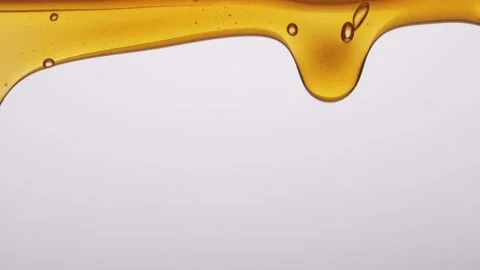 Closeup of thick orange liquid spilling over an edge on a white background Stock Footage 201337403
