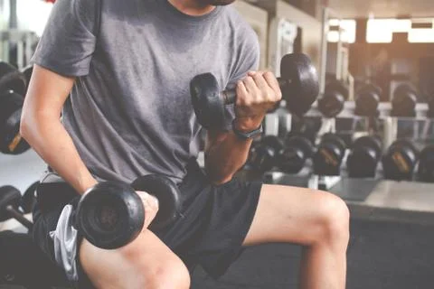 Closeup of a thin man doing exercises with dumbbell. Fitness muscular body. F Stock Photos