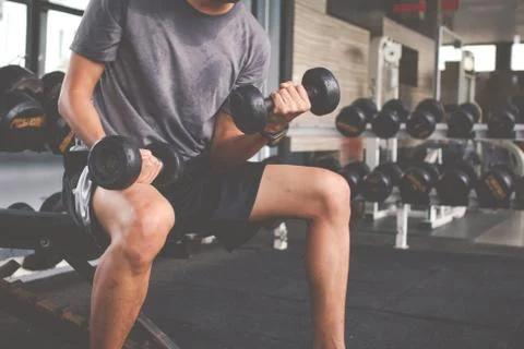 Closeup of a thin man doing exercises with dumbbell. Fitness muscular body. F Stock Photos