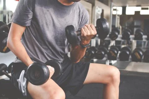 Closeup of a thin man doing exercises with dumbbell. Fitness muscular body. F Stock Photos