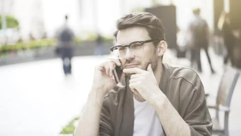 A closeup of thinking young man talking on the phone having a call Foto stock