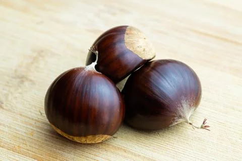 Closeup of three chestnuts on wooden cutting board Stock-Fotos