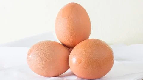 Closeup. Three eggs. Set on a white cloth on a wooden table. 库存照片