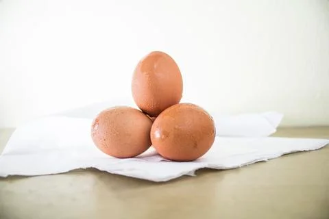 Closeup. Three eggs. Set on a white cloth on a wooden table. Stock Photos