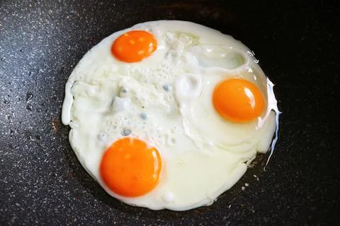 Closeup three of hen eggs being fried in a pan Stock Photos