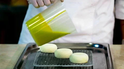 Closeup of three small cakes being covered with green glaze Stock Footage 70308448