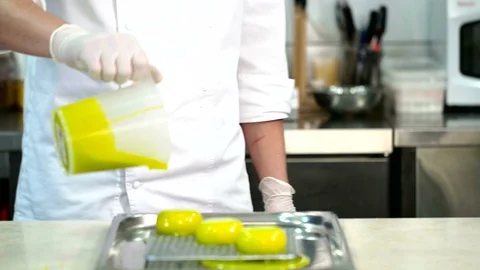 Closeup of three small cakes being covered with green glaze Видео 70308694