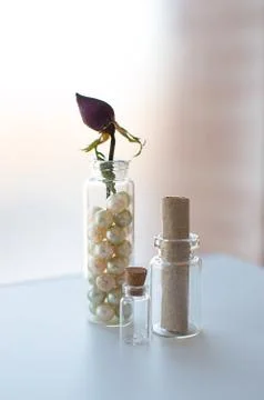 Closeup of three small glass jars with vintage pearls, old parchment and dry  Stock Photos