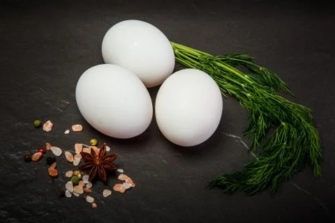 Closeup three white chicken eggs with green dill and spices Stock Photos