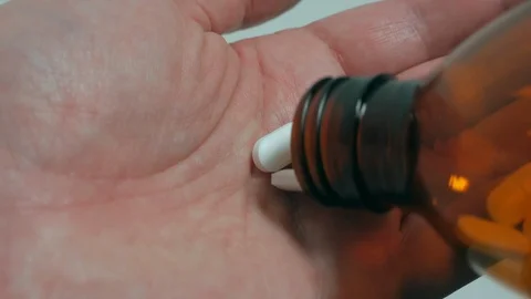 Closeup of three white pills being tipped into hand from medicine bottle Video stock 111479342
