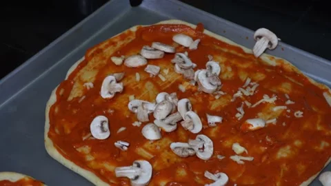 Closeup throwing cut mushrooms in a dough with red sauce to prepare homemade Vídeos de archivo 164580730