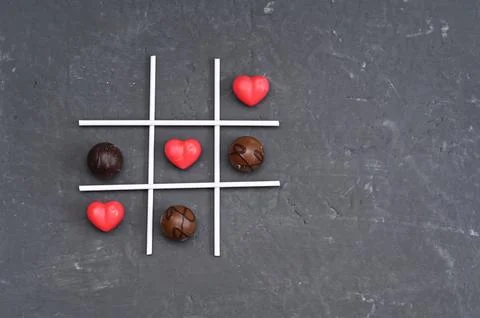 Closeup of tic-tac-toe game with red heart shapes and small round sweets, Foto stock