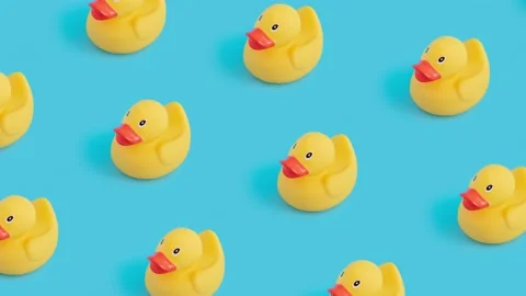 Closeup of tiny duck toys moving against a blue background Vídeos de archivo 221490912