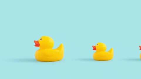 Closeup of tiny duck toys moving against a blue background Vídeos de archivo 221490918