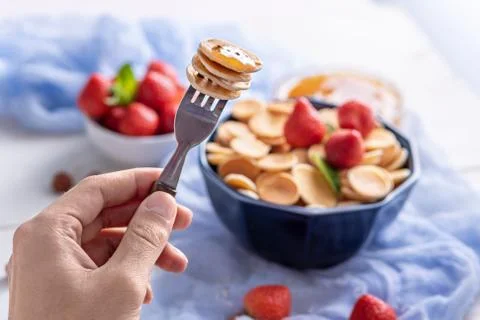 Closeup tiny pancakes cereals on fork, trendy food Stock Photos