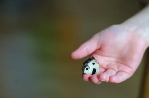 Closeup of tiny plastic house standing on the child's hand 库存照片