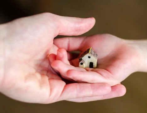 Closeup of tiny plastic house standing on the child's hand Stock Photos
