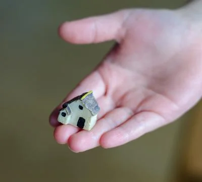 Closeup of tiny plastic house standing on the child's hand Stock Photos