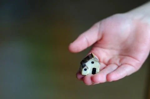 Closeup of tiny plastic house standing on the child's hand on blurred background Stock Photos