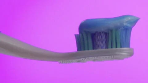 Closeup of Toothbrush with Blue Paste on Pink Background Stock Footage 296142054